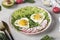 Healthy romantic breakfast - heart-shaped fried eggs served with avocado and radish