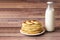 Healthy rustic food. Milk in a bottle, a glass and hot cakes for breakfast. Wheat flour cakes. Wood background