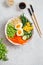 Healthy salad with couscous, carrots, cucumber, green beans, soybeans, corn and an egg on a gray concrete background. Food and