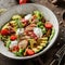 Healthy salad with fillet chicken, avocado, tomatoes, lettuce, greens, pine nuts and sauce in bowl on wooden background. Healthy