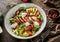 Healthy salad with fillet chicken, avocado, tomatoes, lettuce, greens, pine nuts and sauce in bowl on wooden background. Healthy