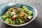 Healthy salad with grilled eggplant, greens, arugula, spinach, lettuce, dried tomatoes and cheese in plate over dark table.