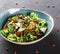 Healthy salad with grilled eggplant, greens, arugula, spinach, lettuce, dried tomatoes and cheese in plate over dark table.