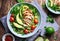 Healthy salad with quinoa, cherry tomatoes, chicken meat, avocado, lime and mixed greens, lettuce, parsley on a wooden table.