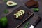 Healthy sandwich on a wooden cutting board with avocado, tomatoes and spices on whole grain bread. Dark background