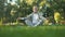 Healthy senior man meditating in park, sitting lotus pose on yoga mat, zen