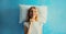 Healthy sleep, happy relaxed sleepy young woman on white soft comfortable pillow thinking looks away imagining she lying on the