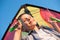 Healthy smiling delightful little kid in shirt holding colorful kite on blue summer sunset sky background during sport leisure