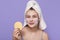 Healthy smiling girl with clear skin, holding beige sponge, wearing white towel, happy young woman covering her skin with facial