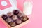 Healthy snack. Energy ball with date plam, black and white sesame, chia and rasin in paper box on pink background. Vegan