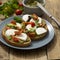 Healthy snack - mozzarella cheese, cherry tomatoes and pesto bruschetta, toast on wooden background. Healthy breakfast ,snack.