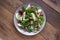 Healthy spinach salad made with red apple, wallnuts, grapes. Wooden rustic background, top view