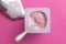 Healthy strawberry fruit flavored pink yoghurt  in small plastic cup isolated on pink background with foil lid - copy space