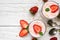 Healthy strawberry yogurt with oats and mint in glasses with fresh berries and spoons over white wooden table