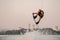 healthy strong man holds cable and skilfully making extreme jump showing trick on wakeboard.