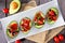 Healthy stuffed avocados with tomato bruschetta, table scene over dark wood