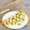 Healthy stuffed omelet. Fried omelet stuffed with tofu cubes and fresh parsley on a plate and a wooden table. Cutlery, burlap