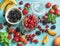 Healthy summer fruit variety. Sweet cherries, strawberries, blackberries, peaches, bananas and mint leaves on blue