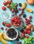 Healthy summer fruit variety. Sweet cherries, strawberries, blackberries, peaches, bananas and mint leaves on blue