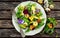 Healthy summer salad with quail eggs, avocado, pecans, wild rocket, red onion and edible viola flowers.