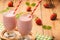Healthy tasty milk cocktails with strawberries on brown wooden background.