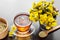 Healthy tea in glass cup closeup, bucket with coltsfoot flowers