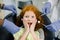 Healthy teeth, caries prevention and pediatric dentistry. Close up of scared funny little red haired curly girl, looking