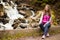 Healthy traveler girl in nature hike. Beautiful young woman happy near waterfall