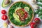 Healthy trendy vegan burrito bowl with white rice, spicy tomato mushroom mix, green arugula, lemon and sliced avocado.
