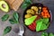 Healthy vegan buddha bowl with falafels, beet quinoa, avocado, and vegetables on dark stone