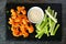 Healthy vegan cauliflower buffalo wings with celery and ranch dip, top view on a slate serving platter