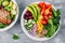 Healthy vegan lunch Buddha bowl. Avocado, quinoa, tomato, cucumber, red beans, spinach, red onion and red paprika vegetables salad