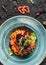 Healthy vegan pumpkin curry salad with with peppers and tomato in ceramic plate over dark background. Healthy food, clean eating,