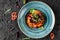 Healthy vegan pumpkin curry salad with with peppers and tomato in ceramic plate over dark background. Healthy food, clean eating,