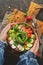 Healthy vegan salad, avocado, celery, cucumber, tomato, radish, nuts and seeds. Girl in denim shirt holding a bowl of vegan salad