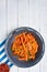 Healthy vegetable carrot fries in an old enamel bowl, chili hot sauce on white boards. Top view.