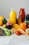 Healthy vegetable and fruit juices or smoothie in glass bottles, ripe slices of orange, apple, red tomato, carrot, celery, avocado