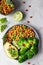 Healthy vegetable lunch of broccoli, roasted chickpeas, avocado, green peas, pomegranate seeds, lime and mint on a ceramic plate.