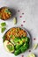 Healthy vegetable lunch of broccoli, roasted chickpeas, avocado, green peas, pomegranate seeds, lime and mint on a ceramic plate.