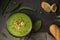 Healthy vegetarian creamy green peas soup with toasted garlic bread, spoon on the table in rustic style. Fresh pea pods