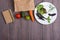 Healthy vegetarian food concept - paper eco bag with healthy various vegetables, plate with greenery and blank notepad for recipe