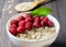 Healthy vegetarian food. Oatmeal with raspberry. Wooden spoon with cereals. Brown wooden background