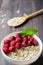 Healthy vegetarian food. Oatmeal with raspberry. Wooden spoon with cereals. Brown wooden background. Vertical photo