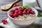 Healthy vegetarian food. Oatmeal with raspberry. Wooden spoon with cereals, milk in a glass, red currant. Brown wooden background