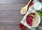 Healthy vegetarian food. Oatmeal with raspberry. Wooden spoon with cereals, milk in a glass, red currant. Brown wooden background