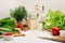 Healthy vegetarian ingredients for spring fresh green salad and kitchenware in white elegant kitchen interior.