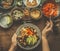 Healthy vegetarian salad bar. Women female hand with spoon puts food on a plate, top view. Healthy lunch