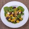 Healthy vegetarian salad with beetroot, green arugula, orange, feta cheese and walnuts on white plate, top view