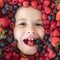 Healthy vitamins fruits. Kids face with fresh berries fruits. Assorted mix of berries strawberry, blueberry, raspberry