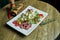 Healthy warm salad with grilled beef and vegetables on a white ceramic plate. Composition with salad and spices on a wooden